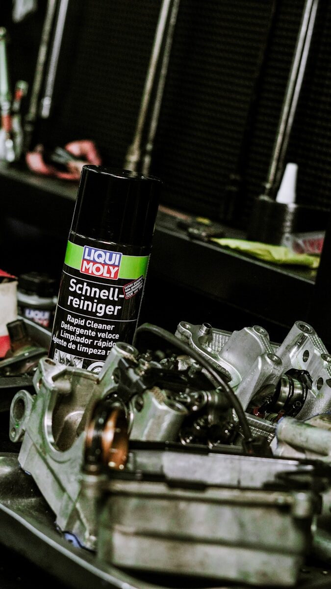 Mechanic's workplace with tools, parts, and cleaning spray.